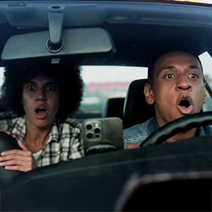 Man and woman with shocked expressions inside a car after an accident